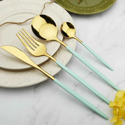 Présentation élégante de couverts vert menthe et dorés posés sur une assiette blanche, incluant couteau, fourchettes et cuillères pour une décoration de table moderne