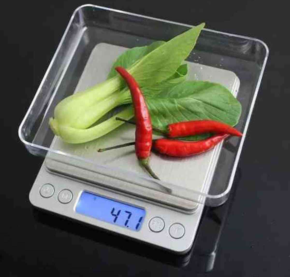 Balance de cuisine Cuisinier Parfait pesant un piment rouge et un bok choy dans son plateau transparent, affichage numérique de 47.1g.
