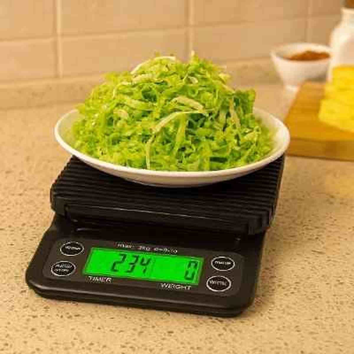 Assiette de chou râpé pesée sur la balance de cuisine noire Précision Gram, affichant 234g sur l'écran LCD rétroéclairé vert.