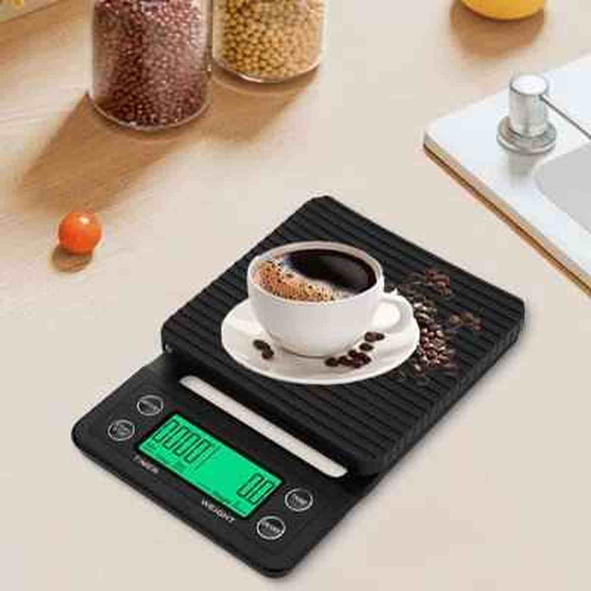 Tasse de café blanc posée sur la balance noire Précision Gram avec écran rétroéclairé vert, idéale pour le dosage précis du café.