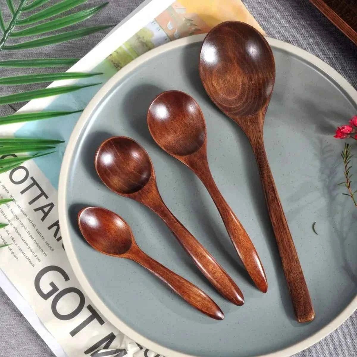 Alignement de quatre cuillères en bois artisanales de différentes tailles (13cm, 15cm, 17cm et 20cm) sur une assiette décorative, montrant le veinage naturel du bois