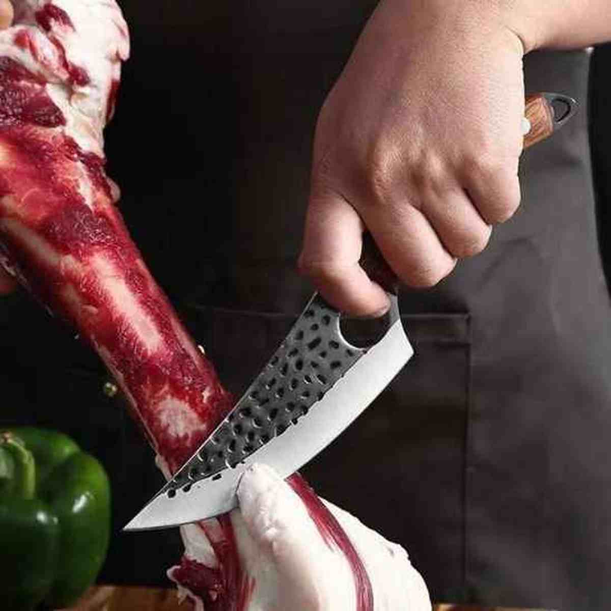 Couteau professionnel Ultra-Cut utilisé pour la découpe d'une pièce de viande avec os, illustrant sa robustesse et sa force de coupe.