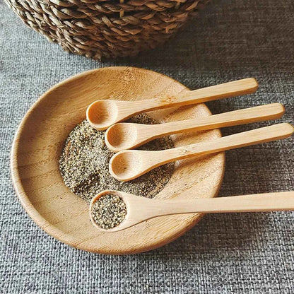 Zoom sur une petite cuillère en bambou naturel contenant des grains de poivre noir, illustrant son usage pour les condiments et épices.