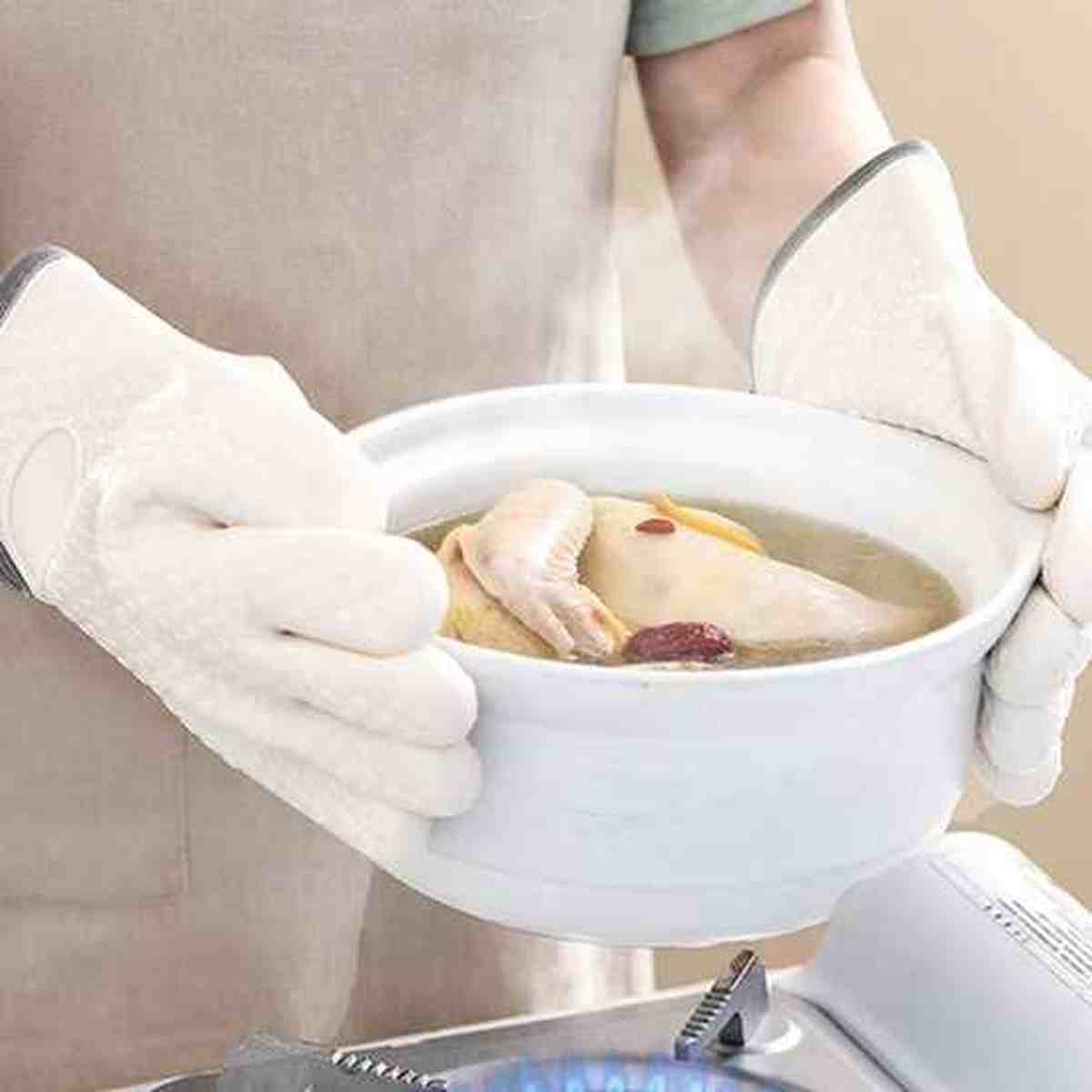 Utilisation des gants de cuisine blancs ThermoProtect pour soulever une soupière chaude, offrant une barrière thermique contre la vapeur et les brûlures.