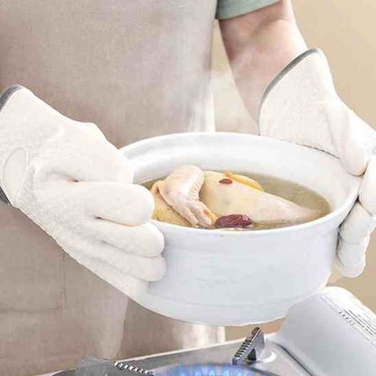 Utilisation des gants de cuisine blancs ThermoProtect pour soulever une soupière chaude, offrant une barrière thermique contre la vapeur et les brûlures.
