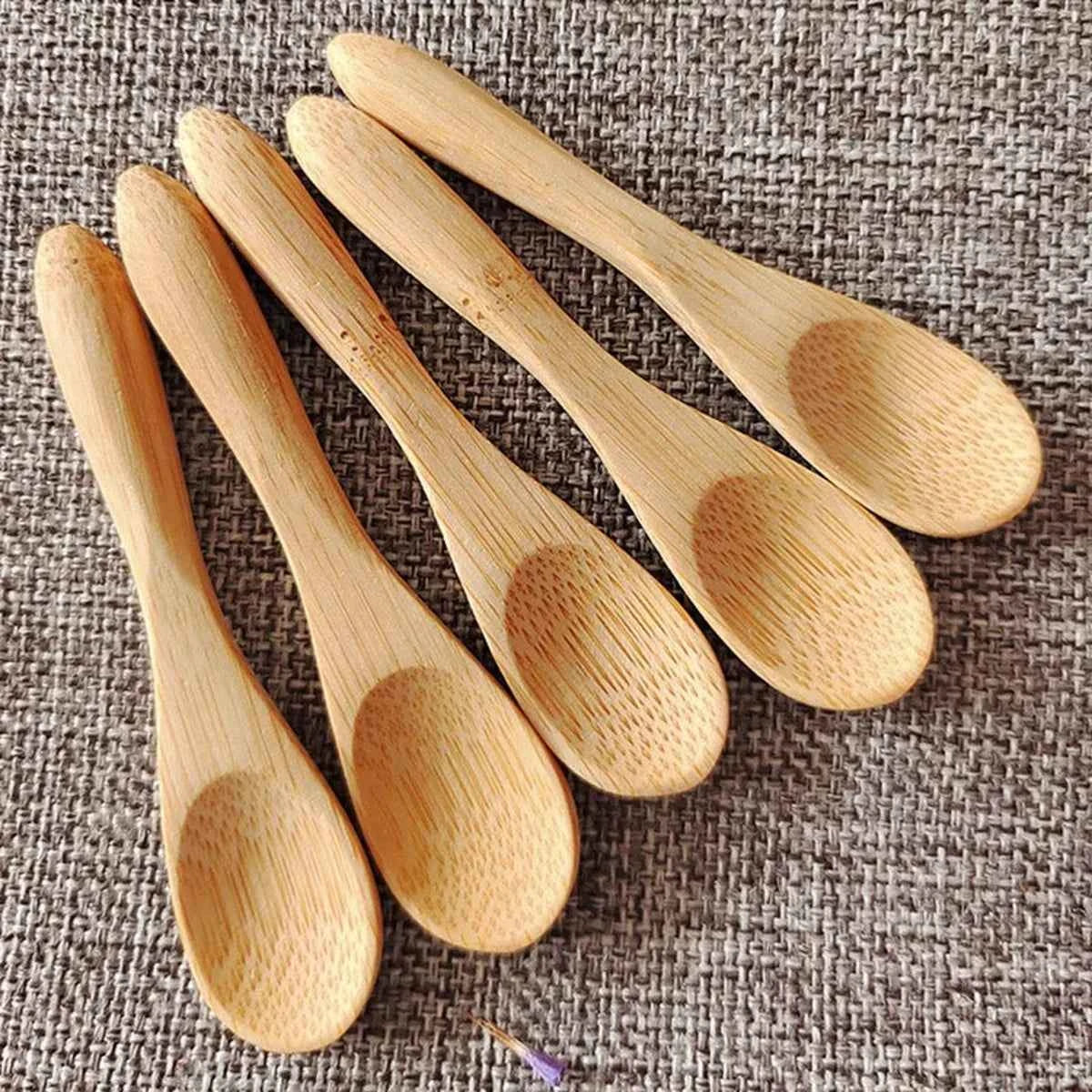 Vue détaillée de cinq petites cuillères en bambou naturel alignées, montrant la texture lisse et la forme ergonomique pour le miel et les condiments.