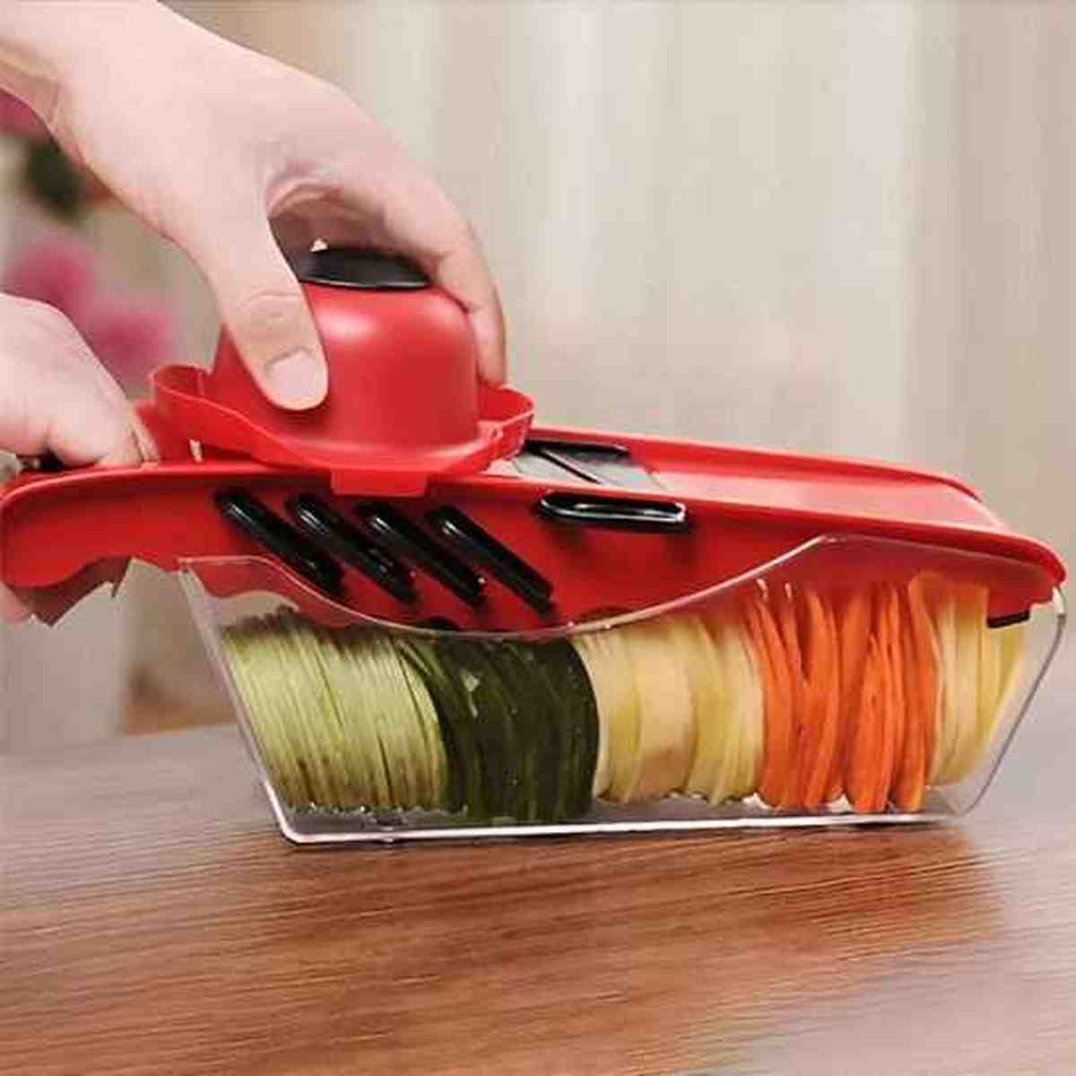 Mandoline de cuisine professionnelle montrant différentes coupes de légumes : rondelles de concombre, bâtonnets de carottes et lamelles de pommes de terre.