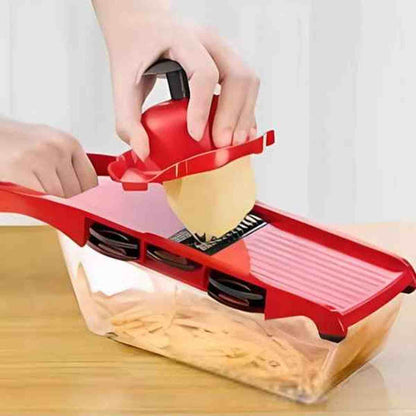 Mandoline de cuisine rouge découpant une pomme de terre directement dans son bac de récupération transparent pour une cuisine propre.