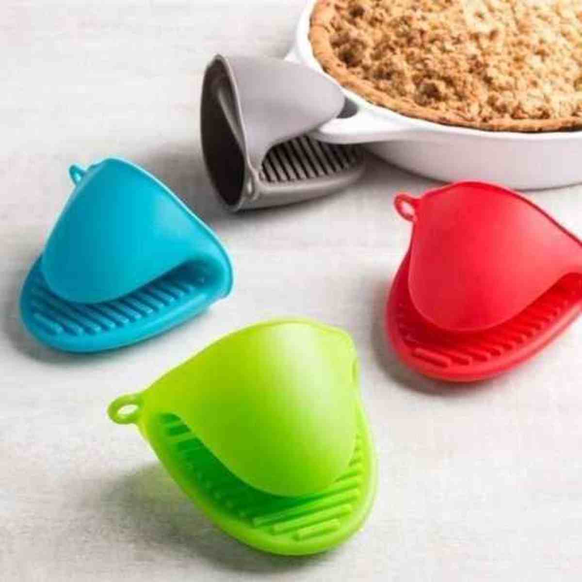Paire de mini gants de cuisine en silicone ThermoShield soulevant un plat chaud, disponibles en vert, bleu et rouge.