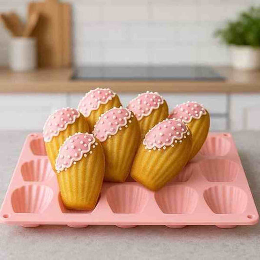 Moule à madeleines en silicone rouge avec 12 empreintes, présenté avec des madeleines dorées et un café pour un petit-déjeuner gourmand.