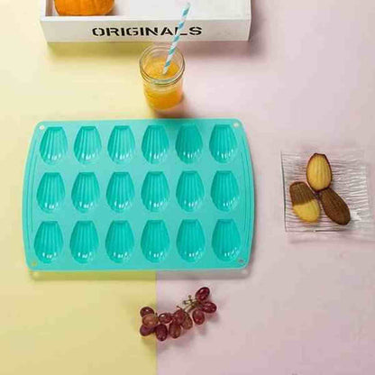 Moule à madeleines 12 cavités en silicone turquoise PâtissiPro, présenté sur une table avec du jus d'orange et des madeleines aux pépites de chocolat.