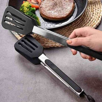 Main tenant une pince de cuisine en silicone noir et acier inoxydable au-dessus d'une poêle, mettant en avant le manche ergonomique et le système de verrouillage.