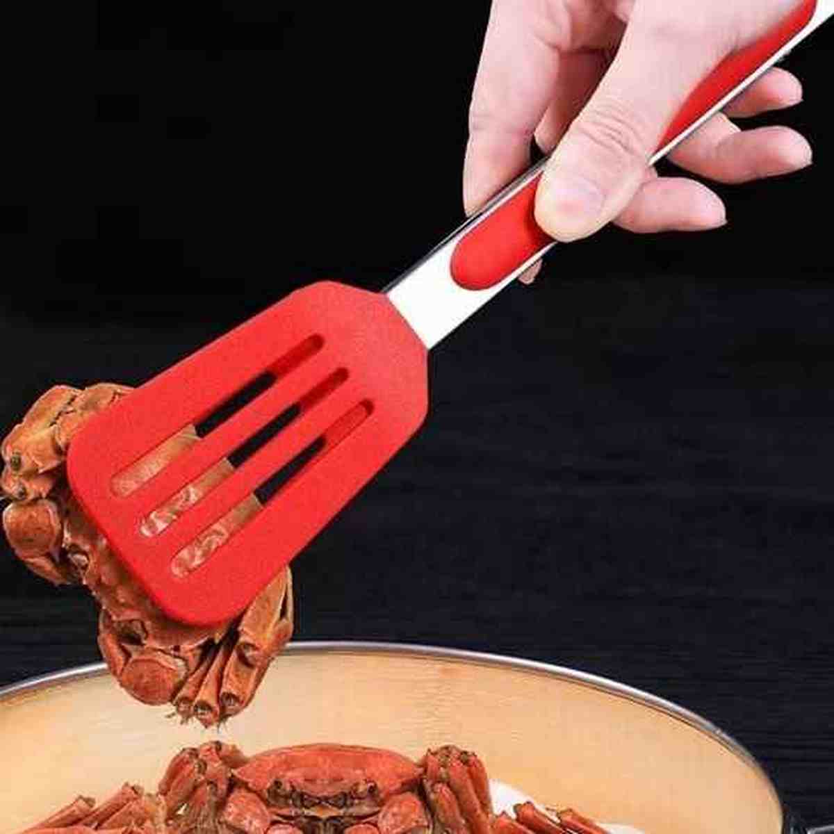 Pince de cuisine en silicone rouge saisissant des crabes dans une casserole, illustrant la force de maintien et la résistance à la chaleur.