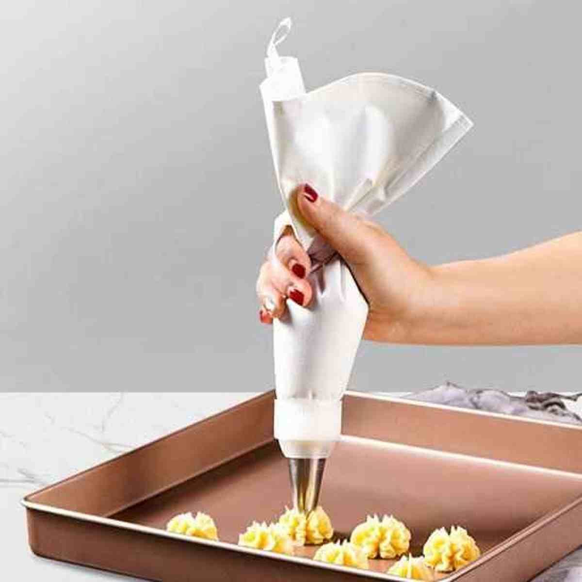 Utilisation de la poche à douille professionnelle Pâtissier Pro en silicone blanc pour une décoration précise de gâteaux et cupcakes.