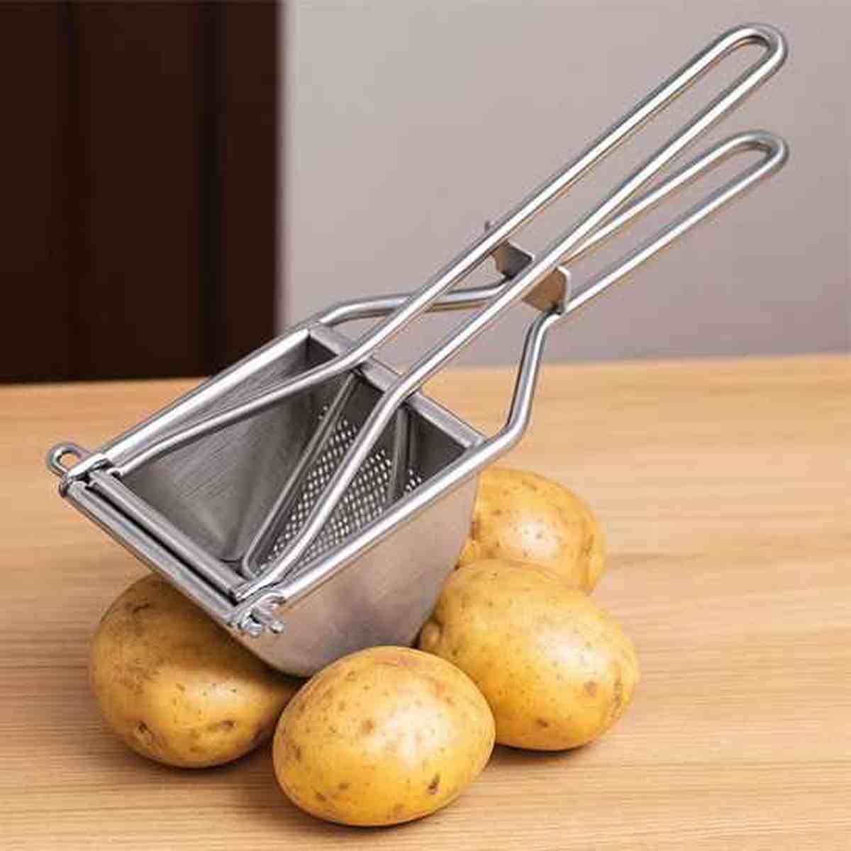 Presse-purée professionnel en inox ouvert avec des pommes de terre entières, prêt pour préparer une purée maison onctueuse