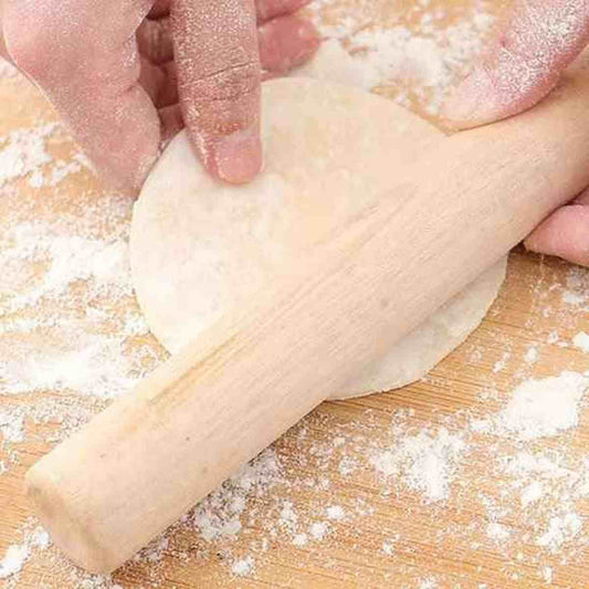 Mains étalant une pâte à l'aide du rouleau à pâtisserie en bois massif Artisan Pro sur un plan de travail fariné.