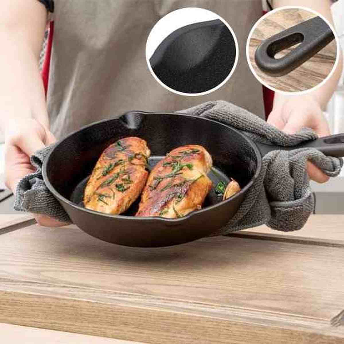 Poêle en fonte tenue avec un torchon contenant deux blancs de poulet grillés, avec des zooms sur le grain de la fonte et le manche ergonomique