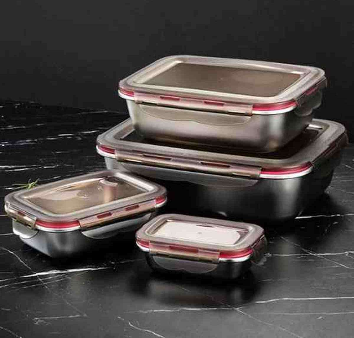 Ensemble de quatre boîtes à lunch en acier inoxydable de différentes tailles avec couvercles hermétiques à joint rose, empilées sur un fond sombre