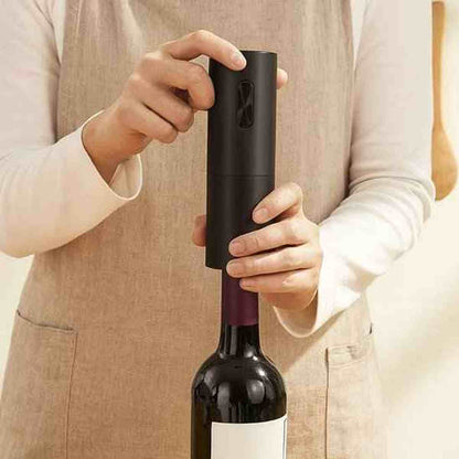 Gros plan sur le tire-bouchon électrique noir extrayant un bouchon de liège d'une bouteille de vin rouge avec facilité.